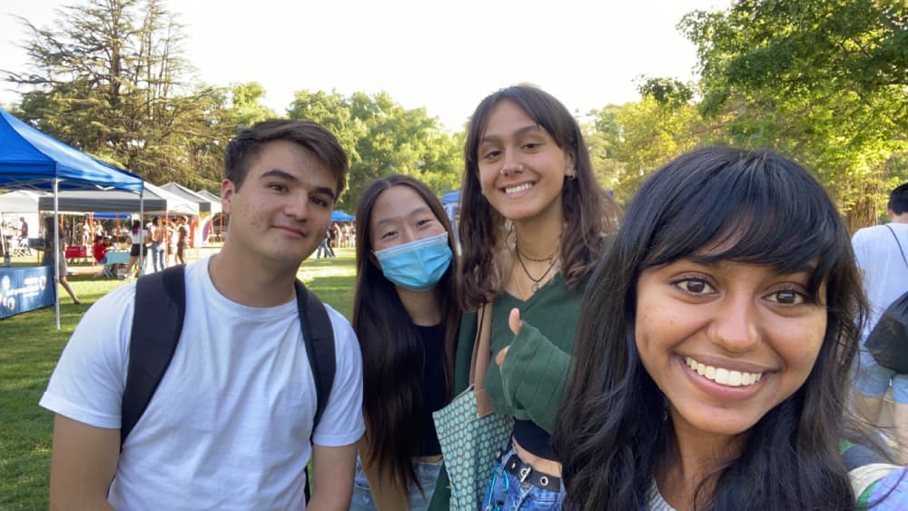 Four undergraduate UC Davis students are taking a selfie in the middle of the campus quad while promoting and educating other students about Joan Viteri Memorial Clinic. 